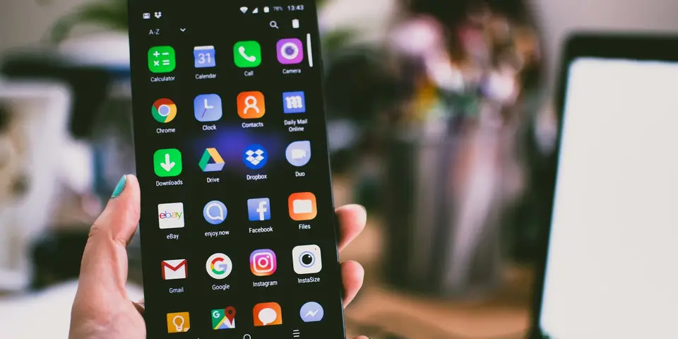 Hand hält ein Smartphone mit geöffnetem App-Raster